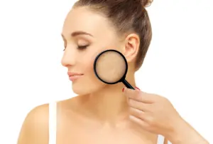 Woman examining her skin with a magnifying glass, highlighting skincare and beauty analysis.